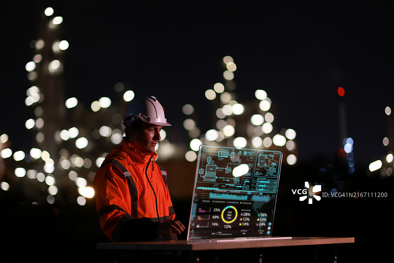 身穿橙色安全夹克和头盔的年轻工程师，在透明屏幕上工作，通过图形输入数据进行创新图片素材