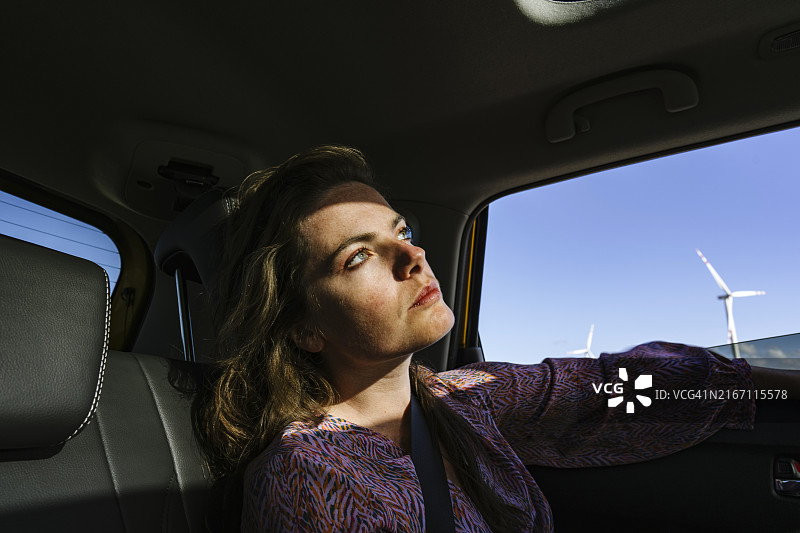 阳光下，坐在汽车后座仰望天空的女性面部特写图片素材