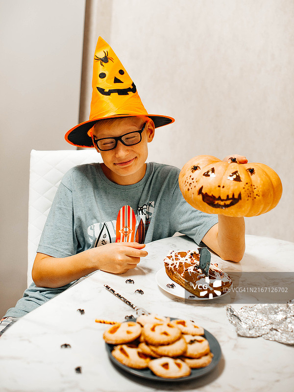 穿着万圣节服装，拿着南瓜和奇怪甜点的青少年男孩图片素材