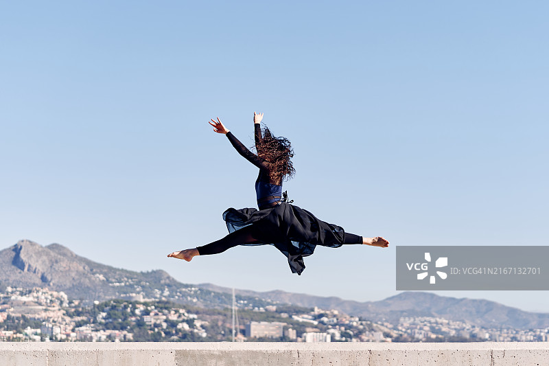年轻女子在城市景观背景下跳跃图片素材