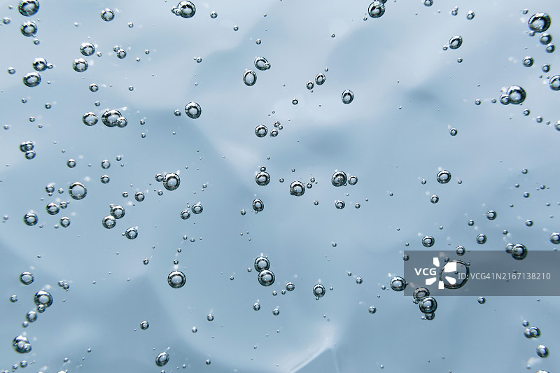 蓝色背景上的透明气泡凝胶霜化妆品，含透明质酸凝胶，顶视图图片素材