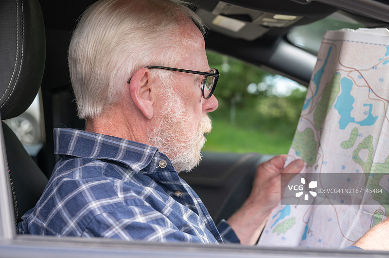 年长的男人坐在车里看着地图图片素材