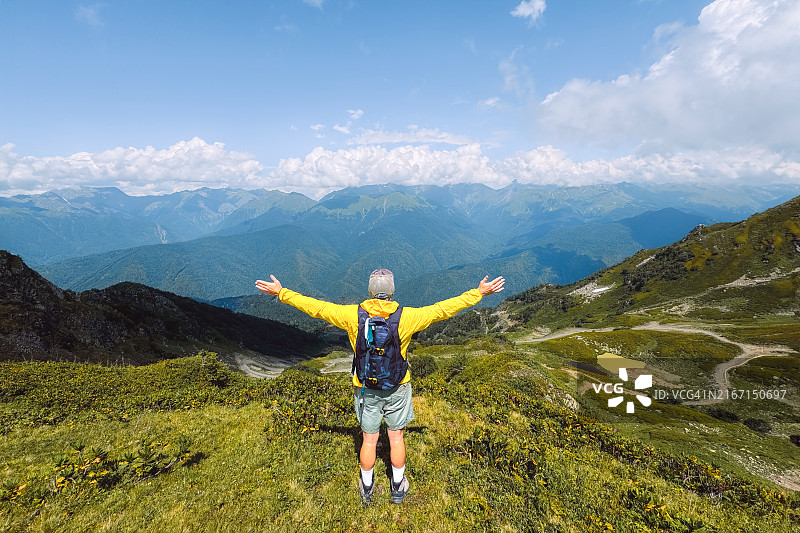 举起双臂，欣赏如画山景的男人图片素材