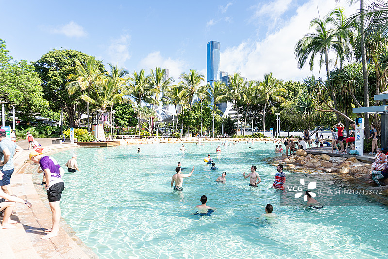 人们在南岸街海滩游泳，背景是布里斯班城市天际线，澳大利亚昆士兰州布里斯班图片素材