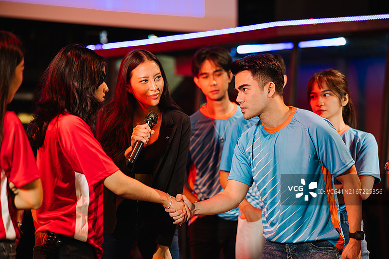 两名亚洲电子竞技团队游戏玩家在舞台上握手图片素材
