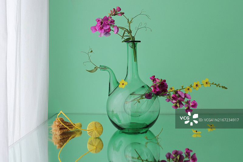 反光表面上的透明绿色玻璃花瓶图片素材