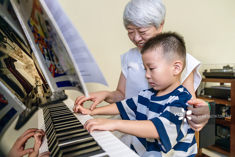 年长的祖母教她的孙子弹钢琴图片素材