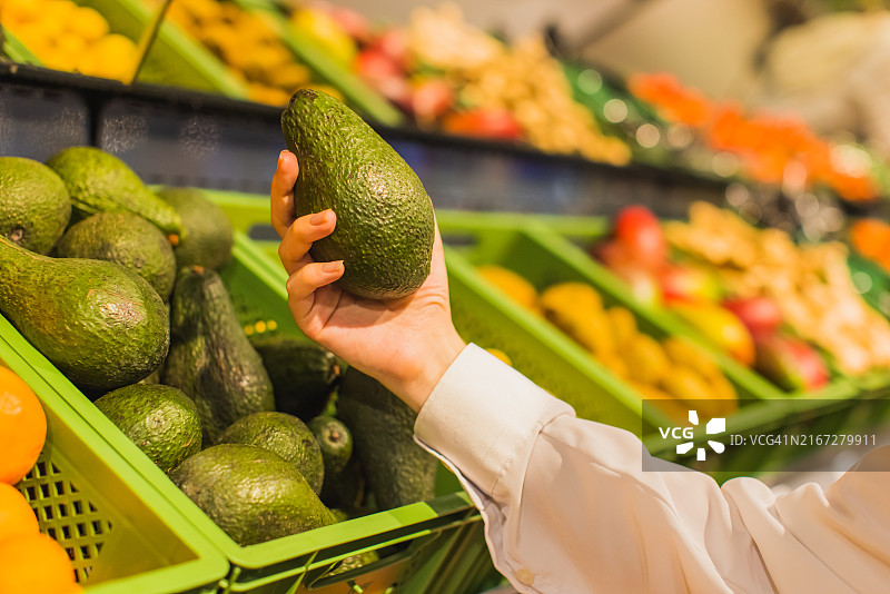 女人在商店里挑选鳄梨图片素材