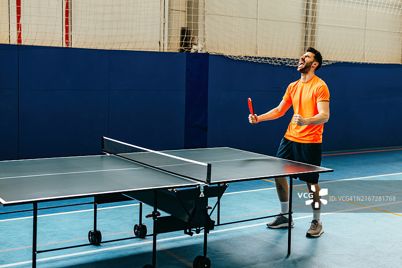 乒乓球比赛中精准发球的运动员，强调橙色球和球拍，捕捉运动的强度图片素材