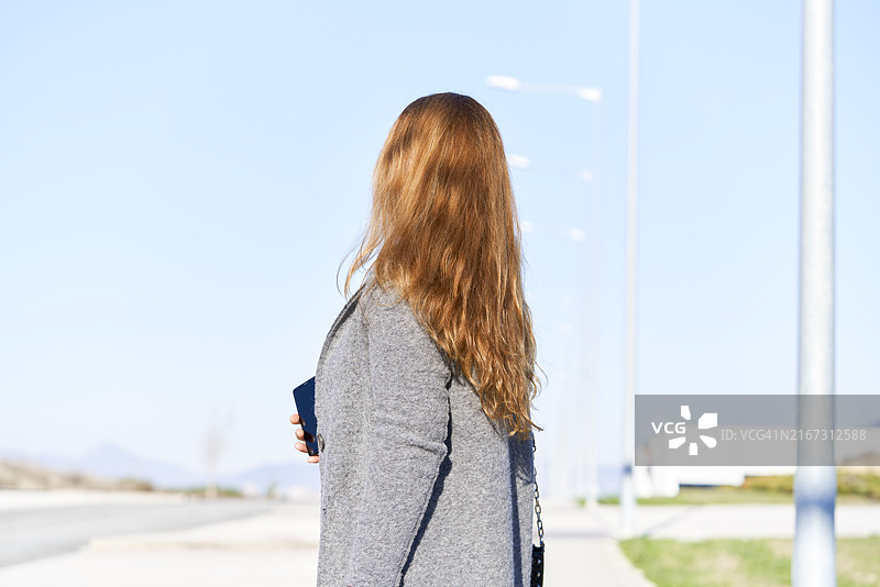 穿着黑色高跟靴站在路上的中年妇女正面照图片素材