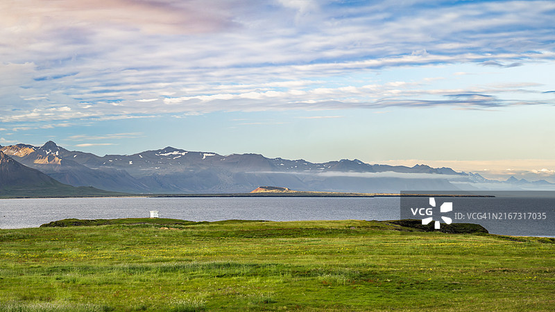 阿尔纳斯塔皮村岩石海岸线日落全景，背景是灯塔和雪山，斯奈山半岛-冰岛西部地区图片素材
