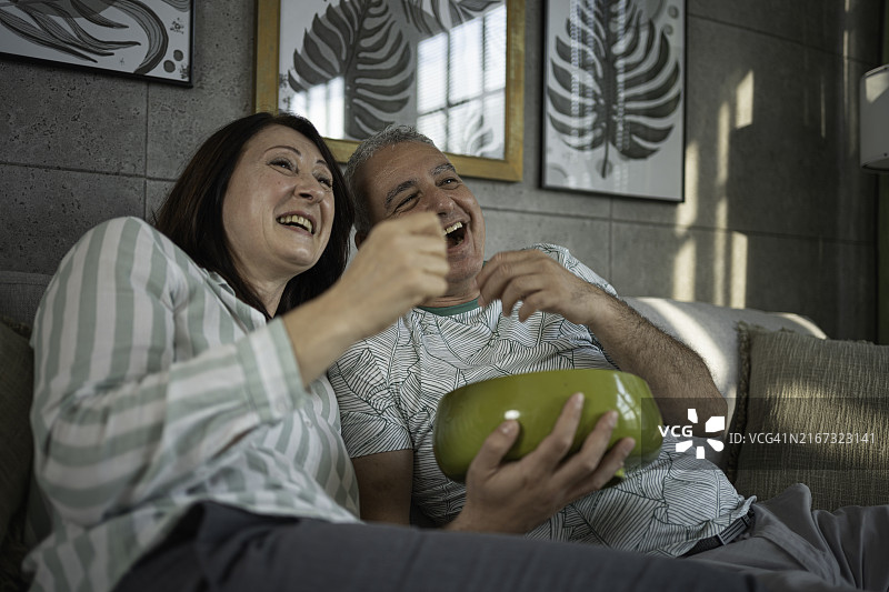 居家观影时光：家人在沙发上一起看电视吃爆米花图片素材