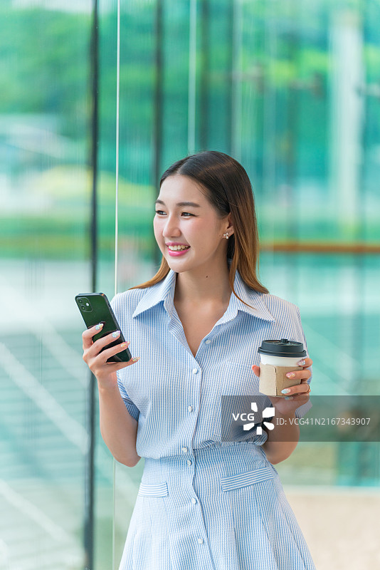 年轻女子喝着咖啡，面带微笑地看着别处图片素材