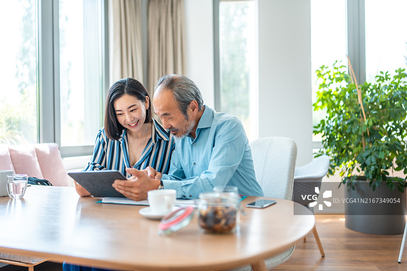 充满活力的亚洲老年男女同事在办公室使用平板电脑图片素材