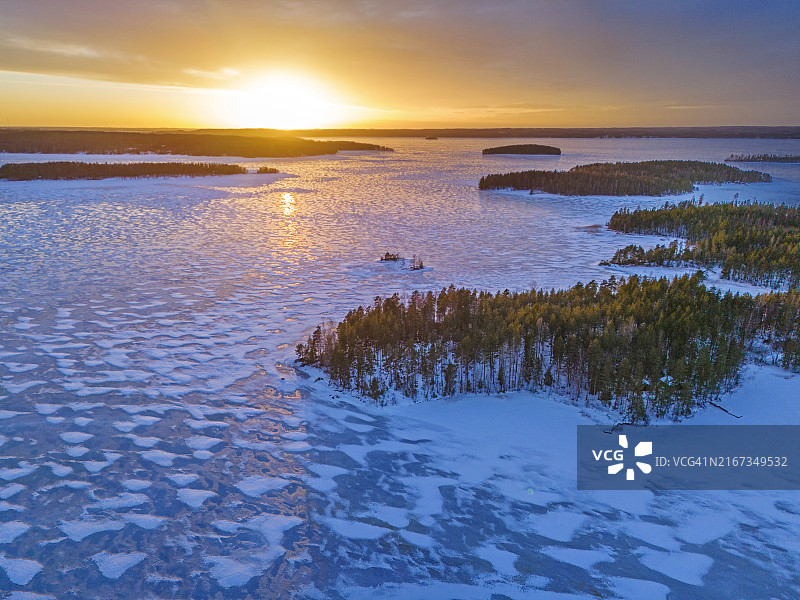 芬兰金色日落下的蓝色冰冻湖面图片素材