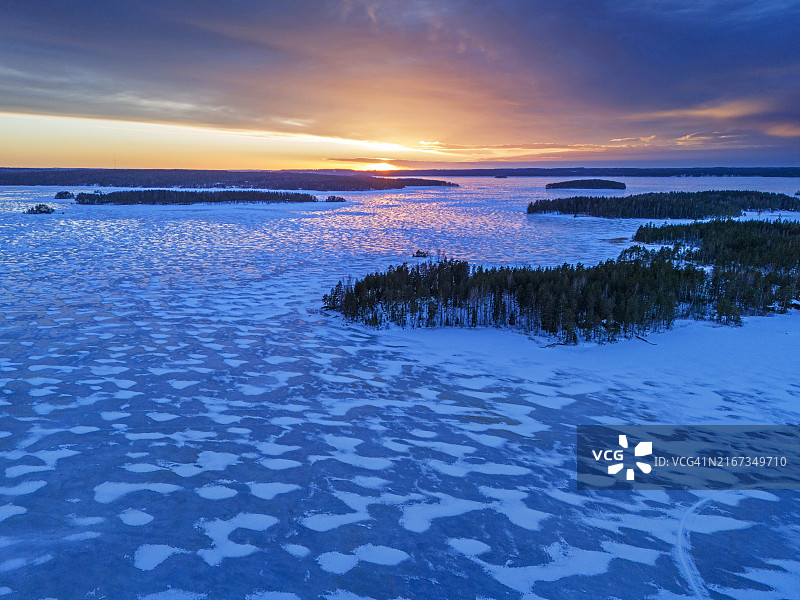 芬兰冬季日落时分的蓝色冰冻湖面图片素材