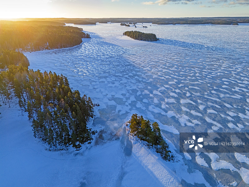黄昏时分，白雪覆盖的冰冻湖面和森林航拍图片素材