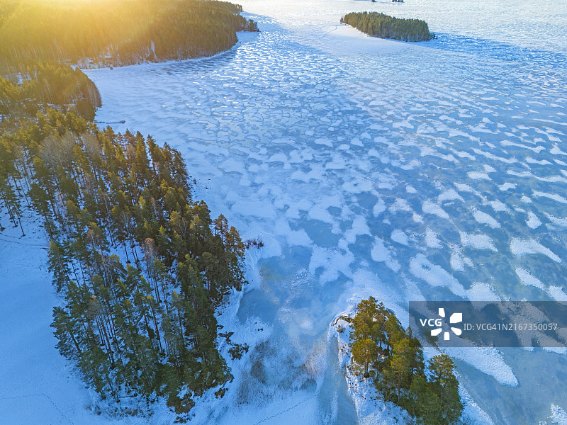 黄昏时分，白雪覆盖的冰冻湖面和森林航拍图片素材