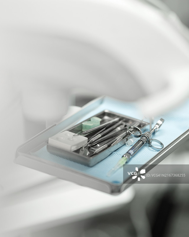 装有牙科器械的金属容器，椅子附近有麻醉注射器。牙医工作工具。牙科诊所。准备接待病人。从上方看。白色背景。柔焦图片素材