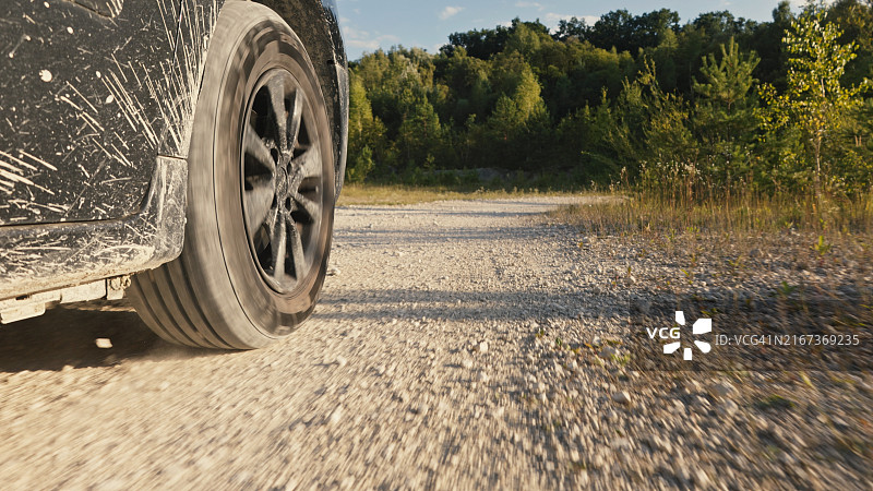 行驶在多尘岩石路上的汽车特写图片素材