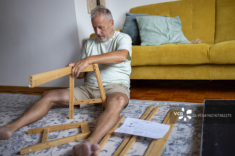 中年男人在家组装家具，安装木椅部件图片素材