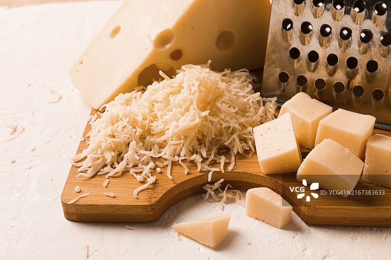 砧板上的马斯丹碎奶酪、磨碎器和奶酪刀，特写图片素材