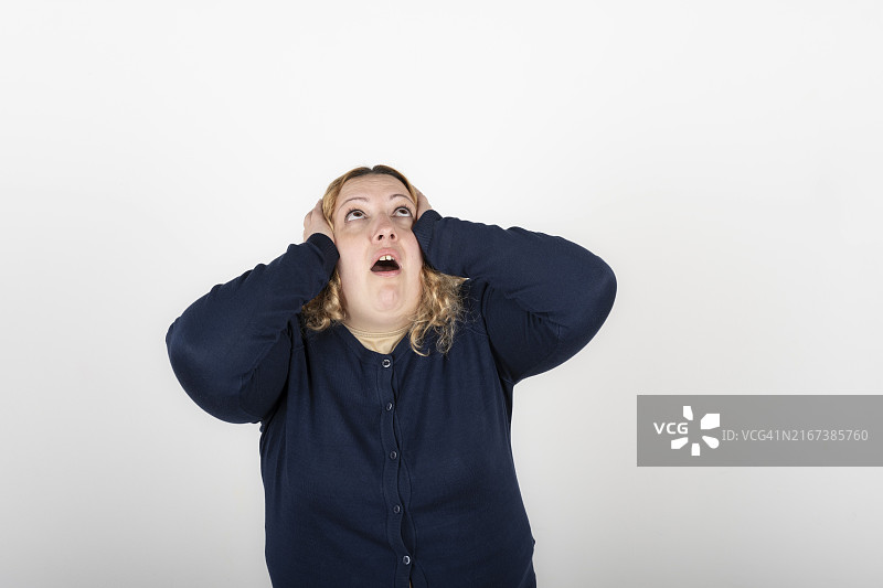 大码身材女人带着疲惫的表情抓住她的头并向上看图片素材