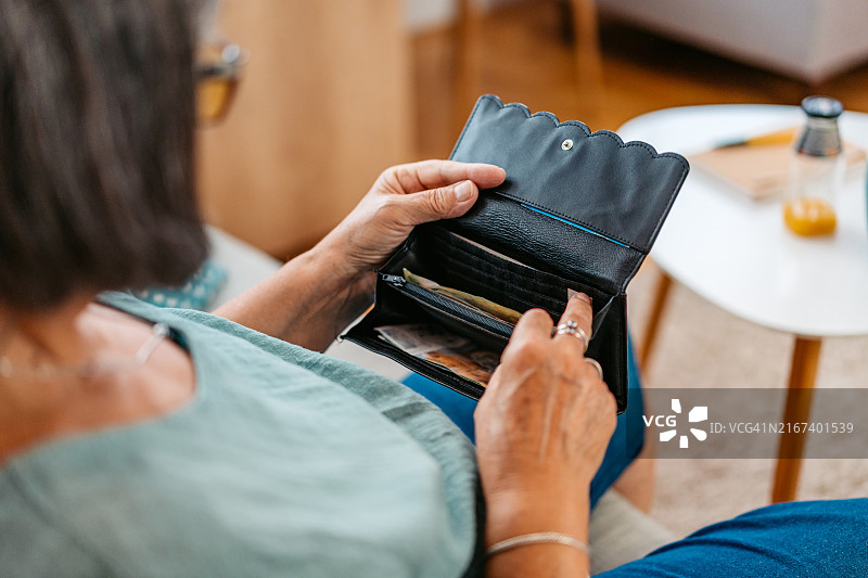 在家中沙发上打开钱包的年长女性图片素材