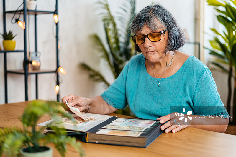 年长妇女在厨房餐桌旁看相册照片图片素材