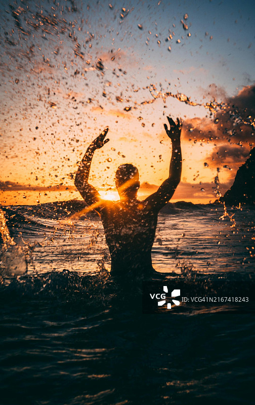 日落时，海边溅起水花的男人剪影图片素材