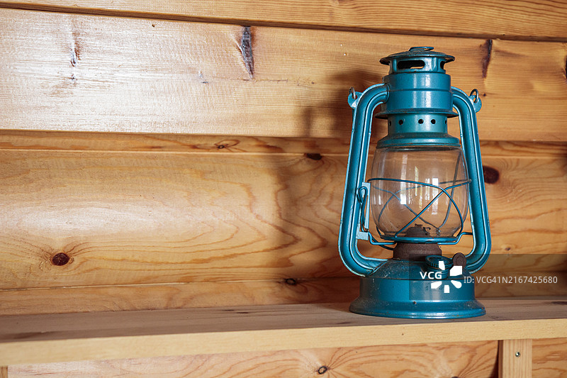 木制乡村房屋内木架上的老式复古蓝色煤油灯图片素材