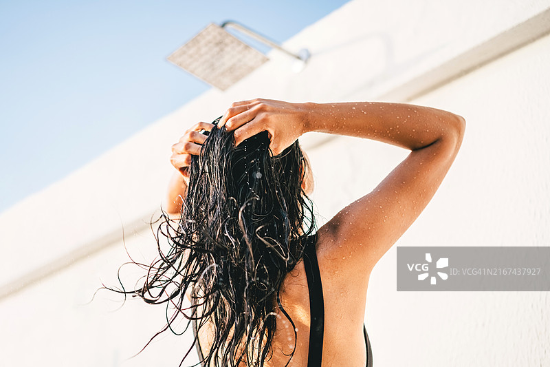 在户外淋浴中洗头发的美丽女子图片素材