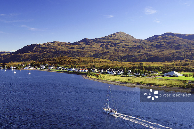 苏格兰高地村庄旁蓝色天空下的帆船图片素材