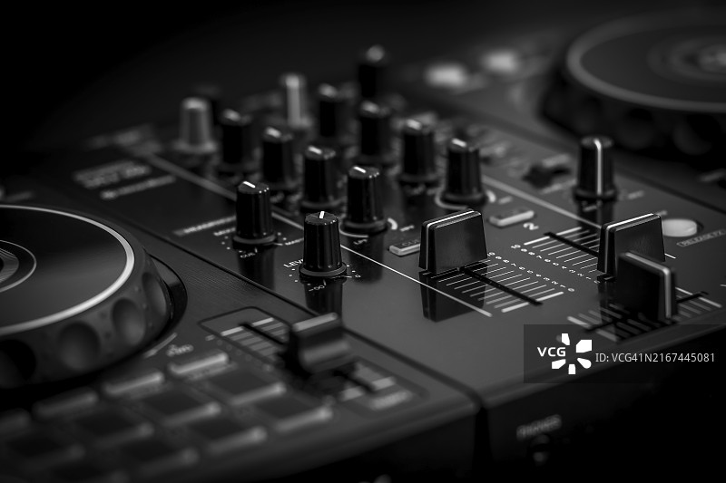 特写：黑白单色调的黑色DJ混音器，配有众多旋钮和推子图片素材