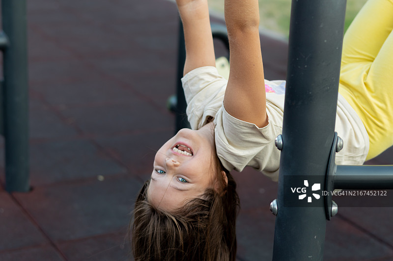 在公司大楼附近公园的户外健身房里，一位长发美丽快乐的女孩肖像图片素材