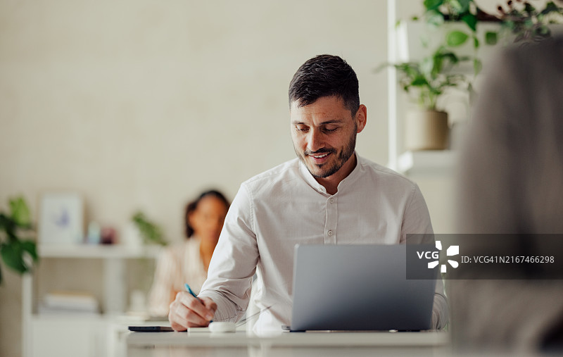 在现代办公室使用笔记本电脑的商务人士图片素材