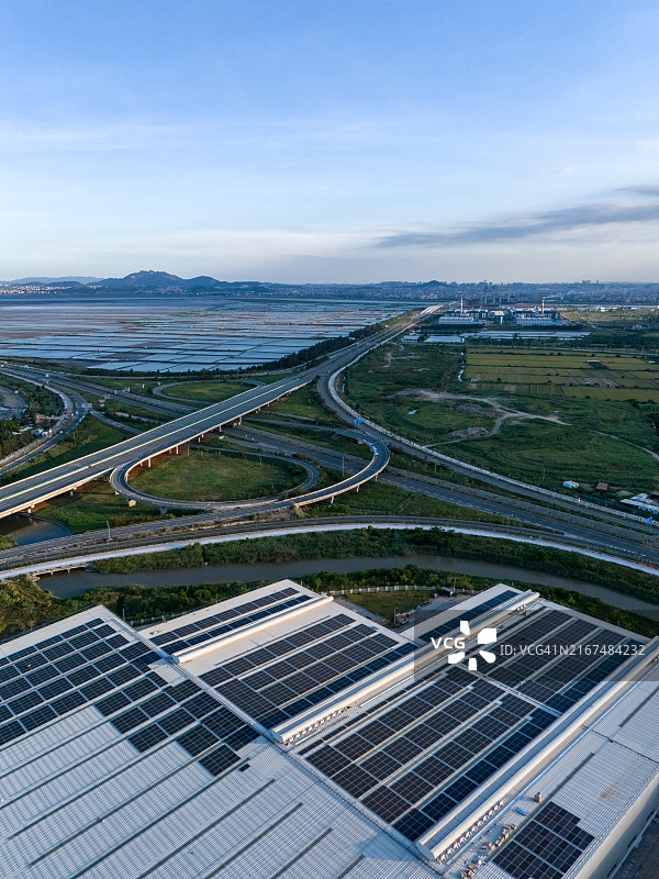 工厂旁的三维交叉桥航拍，工厂屋顶装有太阳能电池板图片素材