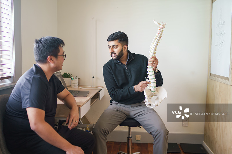 脊椎按摩师向患者展示解剖脊柱图片素材