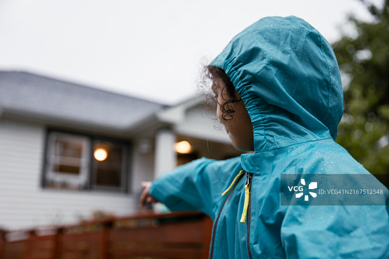 快乐的小女孩在雨中水坑里玩耍图片素材