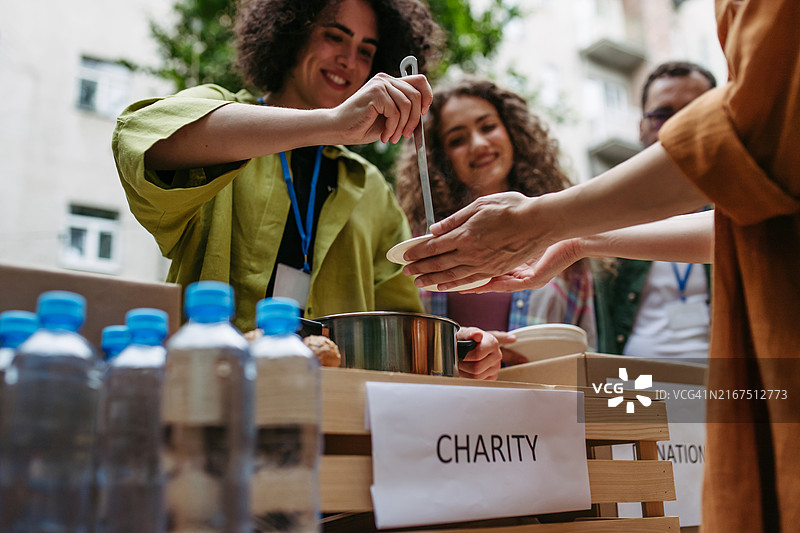 志愿者向需要帮助的人们提供汤，社区用餐计划图片素材