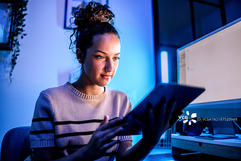 年轻漂亮的女人在深夜在家办公时使用平板电脑图片素材