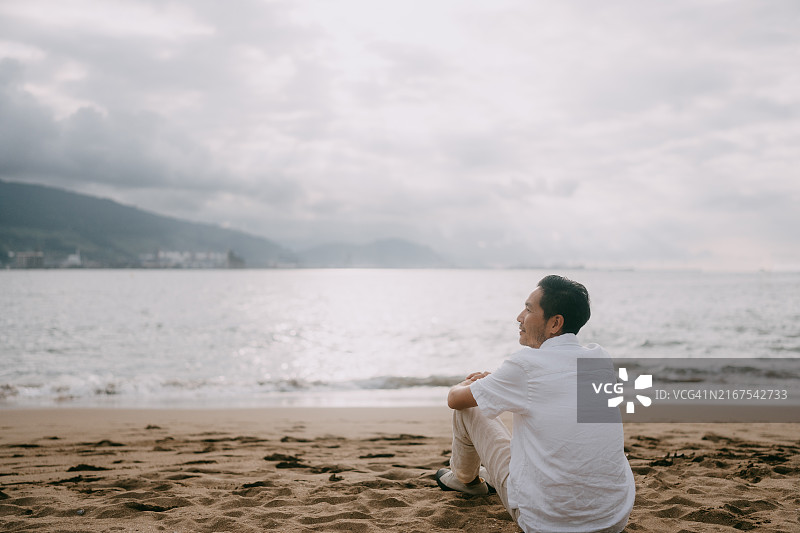 男子坐在西班牙格乔海滩上图片素材