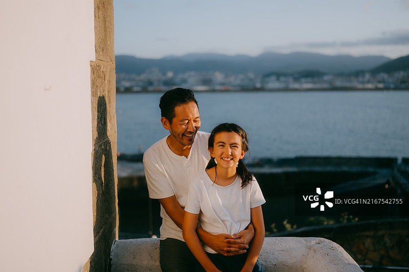 日落时分，西班牙格乔，父亲和年幼的女儿在海边图片素材