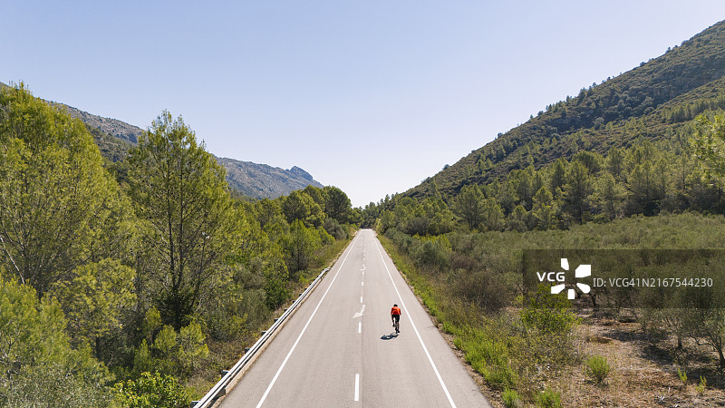 西班牙山区，自行车手在笔直道路上的无人机航拍图图片素材