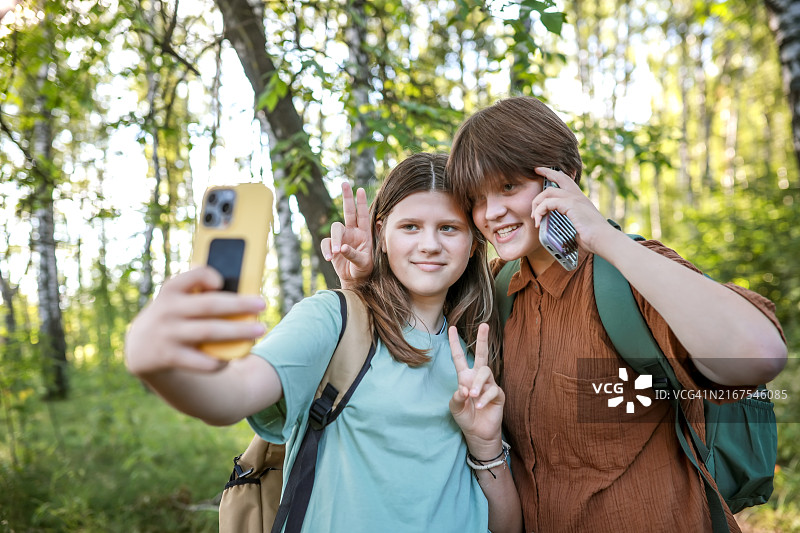 森林探险：青少年背包客在树林中嬉戏自拍图片素材