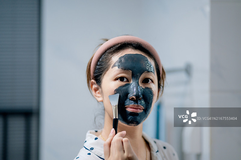 亚裔女性在家清洁面部和敷面膜图片素材