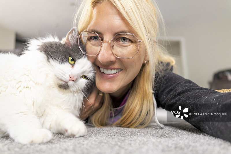 女人在地板上与亲爱的猫咪自拍图片素材