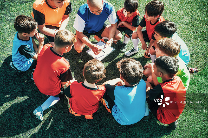 教练在球场上与足球队男孩们讲解比赛计划图片素材