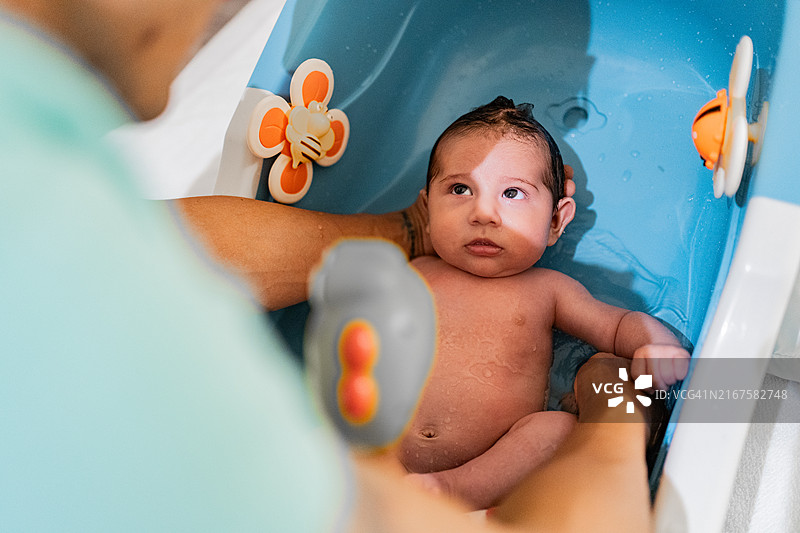 父亲在家中浴缸里给婴儿儿子洗澡图片素材