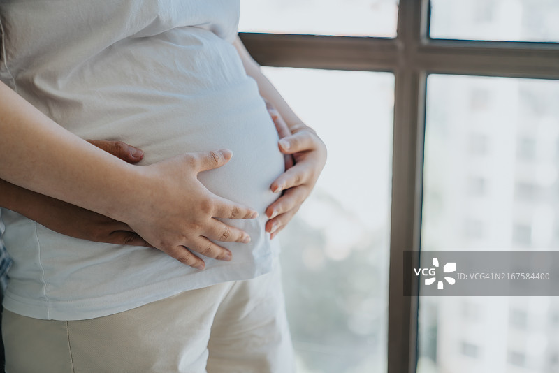 父母双手触摸孕妇腹部特写图片素材